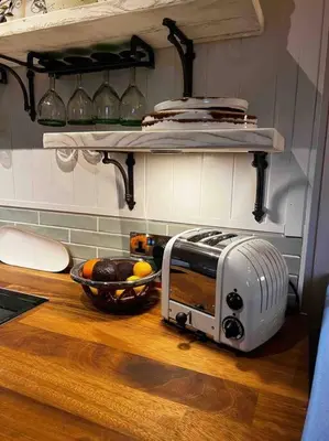 a toaster oven on a counter with a bowl of fruit at Charming stone Bothy at Loch Lomond in Luss