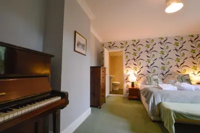 a bedroom with a bed and a piano in it at Cologin Farmhouse in Oban