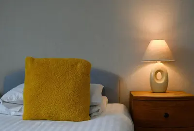 a yellow pillow sitting on a bed next to a lamp at Cologin Farmhouse in Oban
