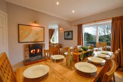 a dining room with a table and a fireplace at Cologin Farmhouse in Oban