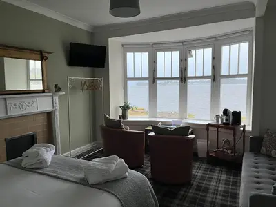 a room with a bed and chairs and a fireplace at The Rhu Inn in Rhu