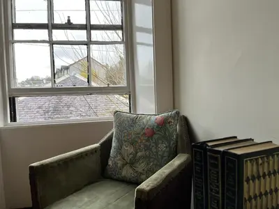 a couch with a pillow sitting in front of a window at The Rhu Inn in Rhu