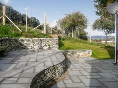a stone walkway with a stone wall and a fence at Sqlarran Cottage in Lochranza