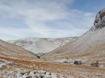 a snow covered hillside with mountains in the background at Sqlarran Cottage in Lochranza