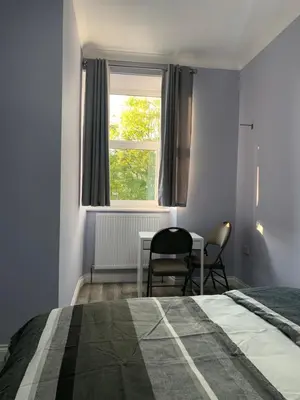 a bedroom with a bed and a table and a window at Ibrox Argyll Inn in Glasgow