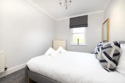 a white bedroom with a bed and a window at JOIVY Modern Flat with Free Parking in Edinburgh