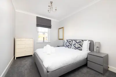 a bedroom with a bed and a dresser and a window at JOIVY Modern Flat with Free Parking in Edinburgh