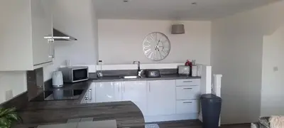 a kitchen with white cabinets and a clock on the wall at Lanarkshire Apartment- Views- Sleeps 4- Balcony in Larkhall