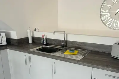a kitchen counter with a sink and a clock on the wall at Lanarkshire Apartment- Views- Sleeps 4- Balcony in Larkhall