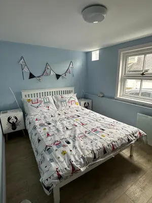 a bed in a blue bedroom with a white bedspread at 3 bedroom cosy cottage in Lamlash, Isle Of Arran in Lamlash