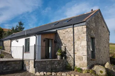 a small stone house with a black roof at Grobdale Byre in Gatehouse of Fleet