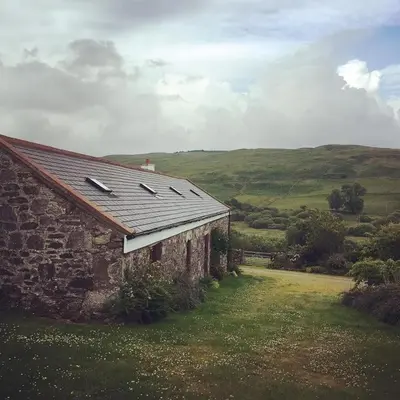 an old stone building with a roof on a field at Grobdale Byre in Gatehouse of Fleet