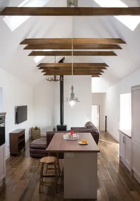 a kitchen and living room with a ceiling with wooden beams at Grobdale Byre in Gatehouse of Fleet