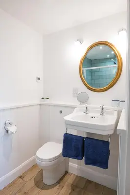 a bathroom with a sink and a toilet and a mirror at Croft Cottage in Gatehouse of Fleet