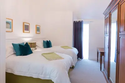 a bedroom with two beds with blue pillows at Dairy Cottage in Gatehouse of Fleet
