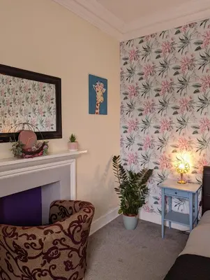 a living room with a fireplace and a chair at Bonnyside House in Bonnybridge