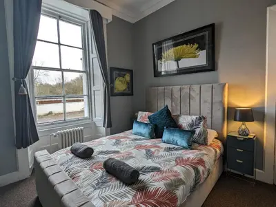 a bedroom with a bed with pillows and a window at Bonnyside House in Bonnybridge