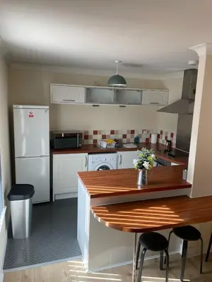 a kitchen with a wooden table and a white refrigerator at Ferry Gait Apartments in Edinburgh