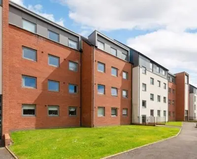 a large brick building with a grass yard in front of it at Ferry Gait Apartments in Edinburgh