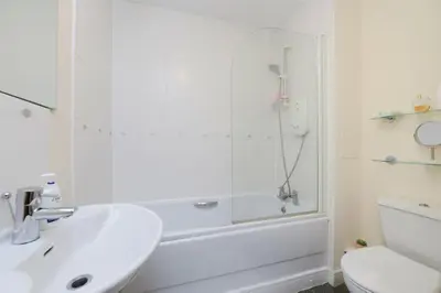 a white bathroom with a shower and a sink at Ferry Gait Apartments in Edinburgh