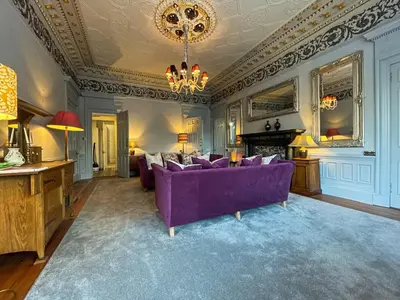a living room with a purple couch and a chandelier at 1 Bed Character Filled Glasgow Apartment in Glasgow