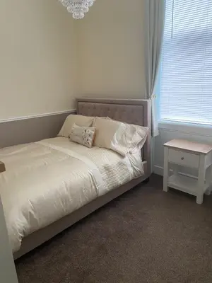 a bed in a bedroom with a table and a chandelier at The Princess Flat, Helensburgh. in Helensburgh