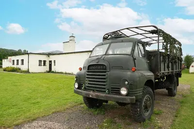 a green truck parked in front of a building at Cultybraggan Hut 37 in Comrie