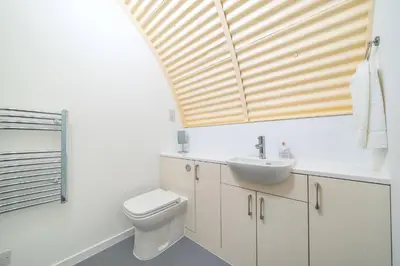 a bathroom with a sink and a toilet and a window at Cultybraggan Hut 36 in Mill of Fortune