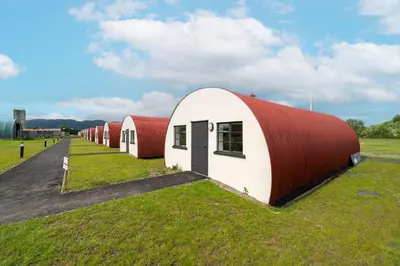 a row of red and white buildings in a field at Cultybraggan Hut 36 in Mill of Fortune