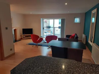 a living room with a table and red chairs at West End & EICC with Parking in Edinburgh