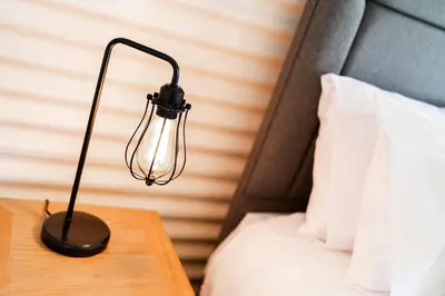 a black lamp on a table next to a bed at Cultybraggan Hut 34 in Mill of Fortune