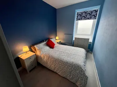 a bedroom with a bed with a red pillow and a window at Anchorage, a lovely 2nd floor one bedroom apartment with fabulous seaviews in Largs