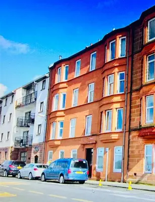 a brick building with cars parked in front of it at Anchorage, a lovely 2nd floor one bedroom apartment with fabulous seaviews in Largs
