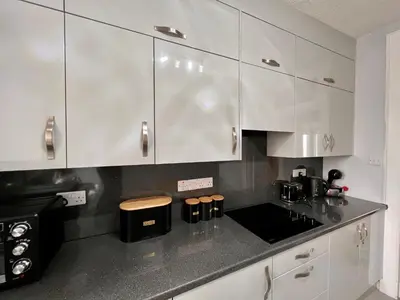 a kitchen with white cabinets and a black counter top at Anchorage, a lovely 2nd floor one bedroom apartment with fabulous seaviews in Largs
