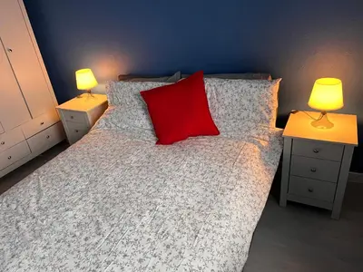 a bedroom with a bed with a red pillow and two lamps at Anchorage, a lovely 2nd floor one bedroom apartment with fabulous seaviews in Largs