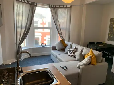 a living room with a couch and a large window at Nelson st (MAYBOLE) in Largs