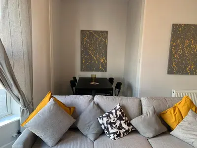 a living room with a couch with pillows and a table at Nelson st (MAYBOLE) in Largs