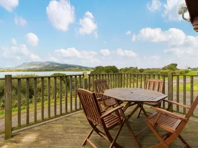 a table and chairs on a deck with a view of the water at Chalet Loch Side Lodge 8 by Interhome in Kinross