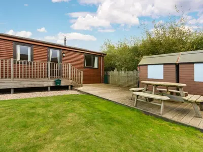 a backyard with a picnic table and a cabin at Chalet Loch Side Lodge 8 by Interhome in Kinross