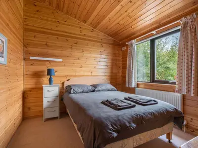 a bedroom with a bed in a wooden cabin at Chalet Loch Side Lodge 8 by Interhome in Kinross