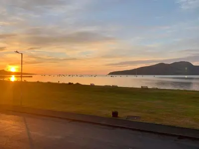 a sunset over a body of water with a park at This must be the place - Arran, Lamlash in Lamlash