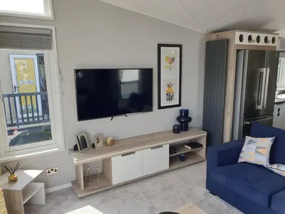 a living room with a tv and a blue chair at Machrihanish Holiday Park in Campbeltown