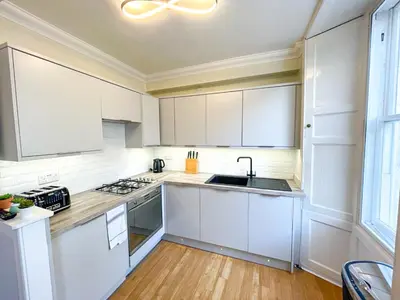 a kitchen with white cabinets and a sink at Rose Street's Hidden Treasure- 2Bed Newly Refurbished Apt in Edinburgh