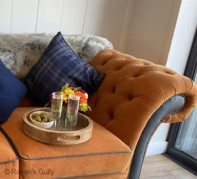 a brown couch with a tray of drinks on a table at Raven's Gully - Brodick, Isle Of Arran in Brodick