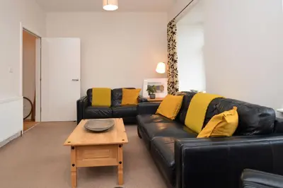 a living room with a black leather couch and a coffee table at Pedals and Paddles in Innellan