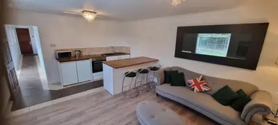 a living room with a couch and a kitchen at Laighdykes Guest Cottage in Saltcoats
