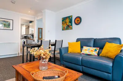 a living room with a blue couch and a table at Lovely 3-bedroom flat with free parking in Bridge of Allan