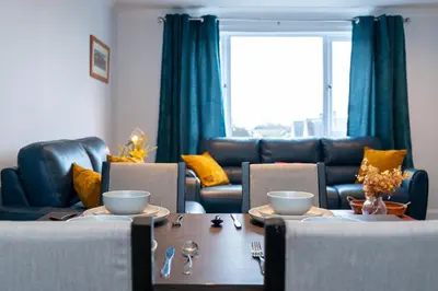 a living room with a table and chairs and a couch at Lovely 3-bedroom flat with free parking in Bridge of Allan