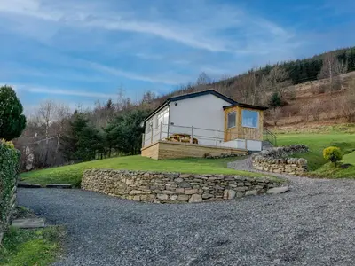 a house on a hill with a stone wall at Ciaran Cottage in Stron-fearnan