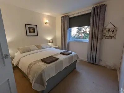 a bedroom with a large bed and a window at Two bedroom flat in Bridge of Allan, Stirling in Bridge of Allan